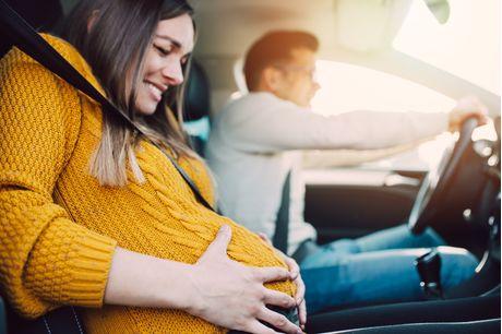 A pregnant woman starting to feel pain and contractions while her worried husband is driving a car.