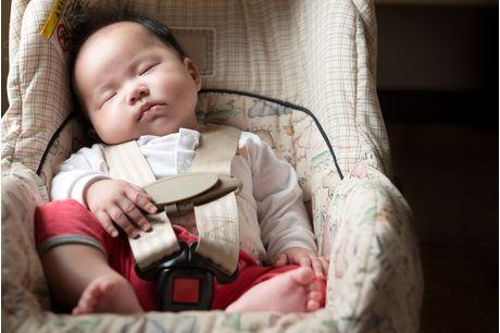 Infant fastened with seat belt for safety purpose in car seat going to well-baby visit.