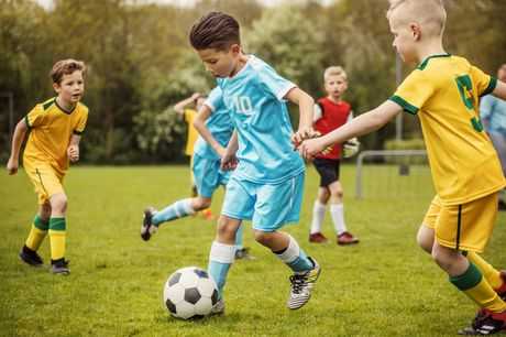 Group of children in uniforms playing outdoor soccer