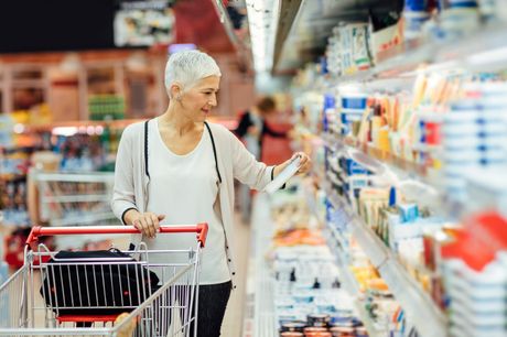 Woman reading food label shopping in a grocery store.  