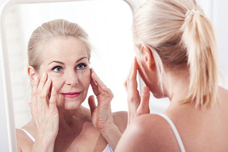 Woman looking in the mirror and considering Botox
