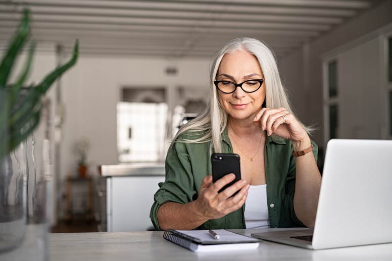 Woman on phone in front of computer at a table.