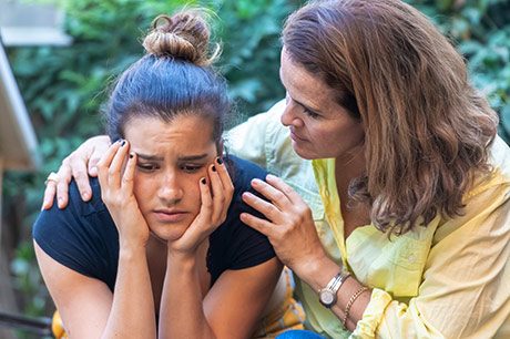 Mother consoling daughter over COVID-19 pandemic