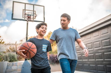 Father and son playing basketball in their driveway. 