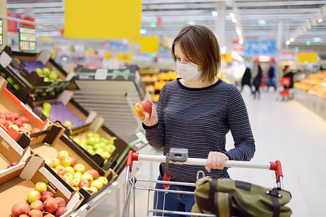 Woman grocery shopping safely to avoid the spread of coronavirus