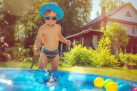 Toddler boy filling kiddie pool in the backyard