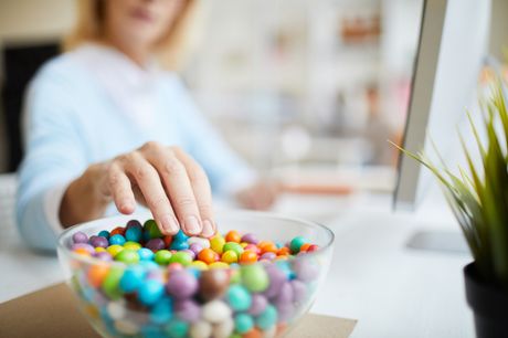 A hand reaching for candy while stressing about quarantine weight