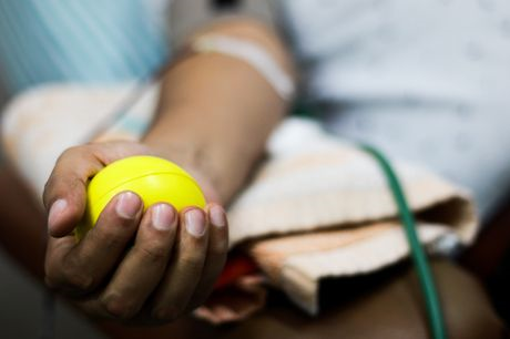 Man squeezing a ball in his palm while donating blood plasma