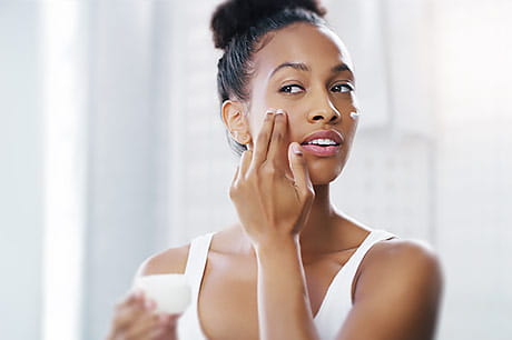 Young woman applying moisturizer