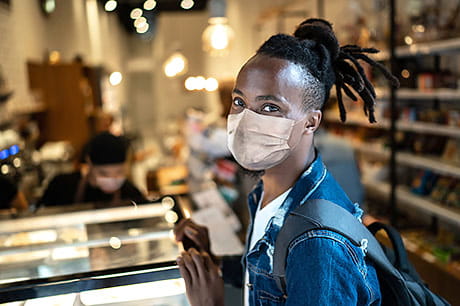 Young male wearing a mask in a neighborhood deli.