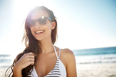 Smiling woman sunglasses on a beach