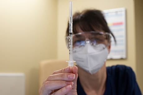 A healthcare worker holding a COVID-19 vaccine