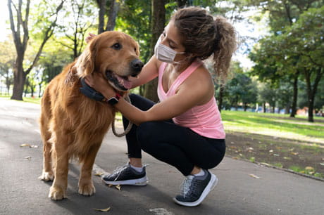 Woman in mask walking her dog outside