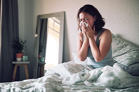 Woman sneezing in bed