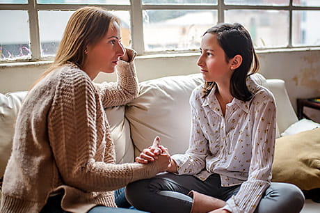 A mother and her daughter, smiling and talking.