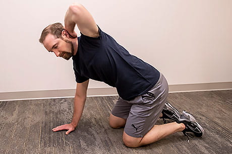 Performing a mid-back rotation stretch to prevent tightness.