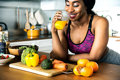 A woman enjoying a glass of fresh-squeezed orange juice following her exercise routine.