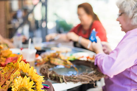 Two women creating floral wreaths in a crafting class.