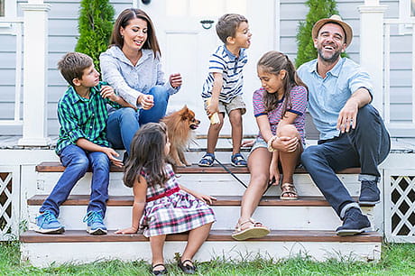Family of six enjoying some time together on the front steps of their home.