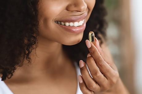 A young woman taking a fish oil supplement.
