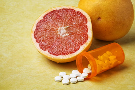 medication on a yellow background with a grapefruit next to the bottle 