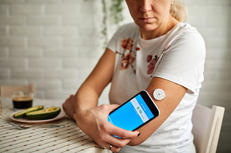 woman wearing digital glucose monitor on her arm