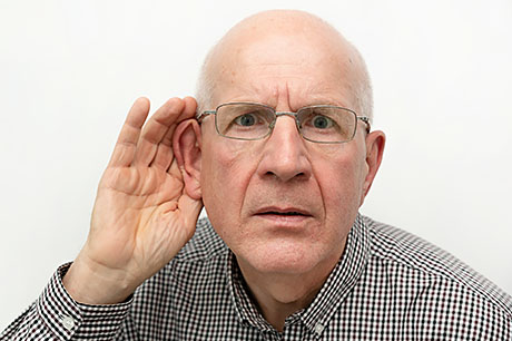 An elderly man struggles to hear conversation.