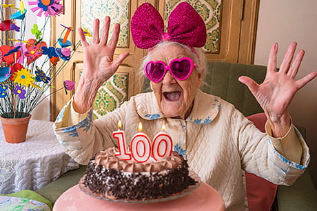 An exuberant elderly woman celebrates her 100th birthday.