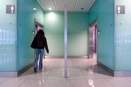 A woman enters a public restrooms.
