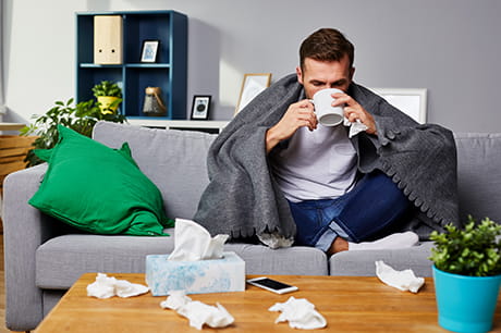 man drinking hot tea with tissues