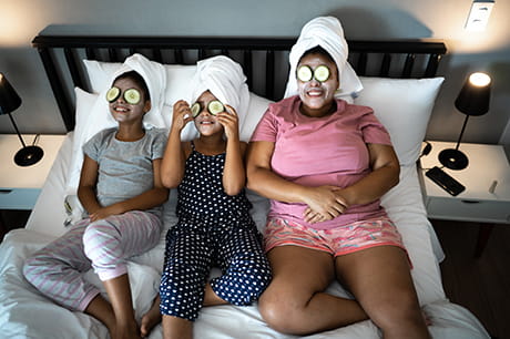An image of a family relaxing with facemask and cucumbers on their eyes