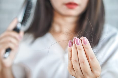 picture of a woman examining hair loss. 