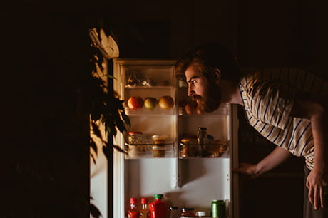 An image of a girl looking in the refrigerator for a late night snack. 