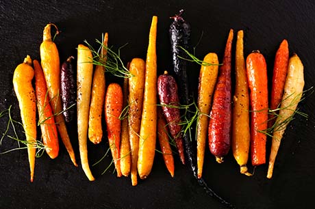 Artistic image or carrots and dill with a black background