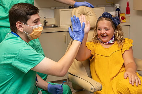 A young female patient gives a high-five to her healthcare provider following a successful medical appointment.