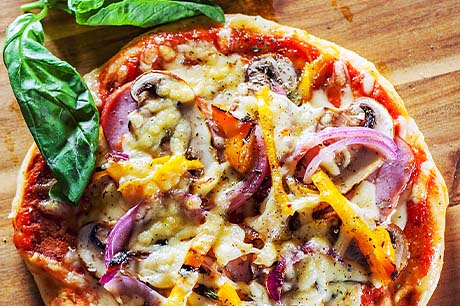A delicious pita pizza with numerous toppings is hot and ready to eat.