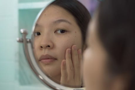 a woman checking her skin in the mirror
