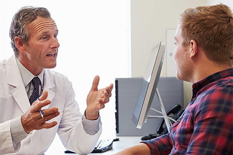 Male physician consults a young male patient regarding drug use and supplement consumption.
