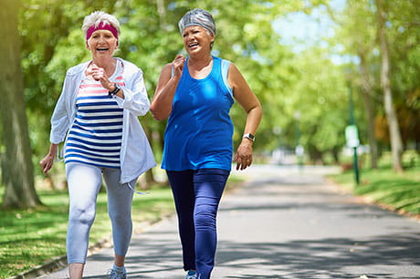 Two women enjoying a brisk walk in the park.