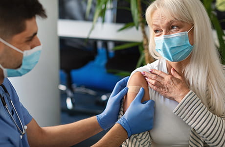 A mature adult woman receiving an RSV vaccine from a male healthcare professional.