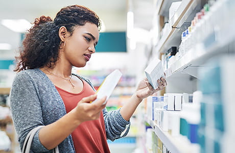 A woman reviews the active ingredient label on an over-the-counter decongestant medication.