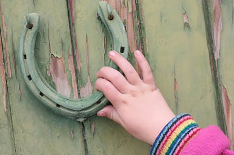 A young girl touches a green horseshoe.