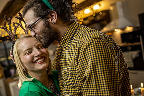 A young couple shares an embrace as they celebrate at  a holiday dinner.