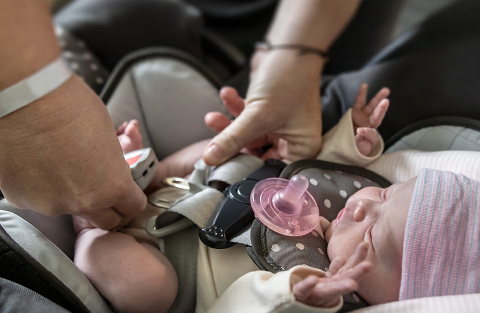 Father putting baby in car seat