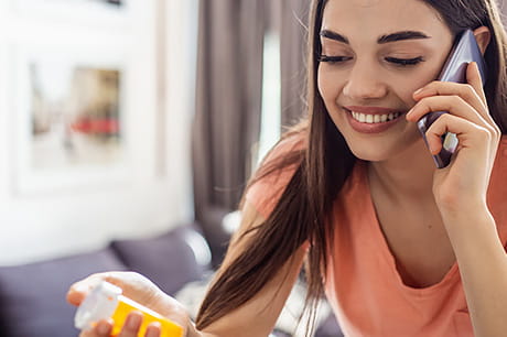 A young woman refills her prescription over the phone.