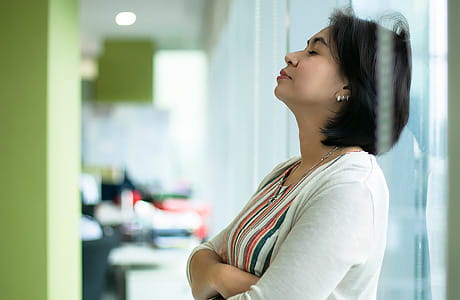 A woman leans against an office wall in an effort to cope with stress at work.