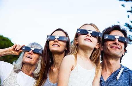A family wearing eclipse glasses and staring at the sky.