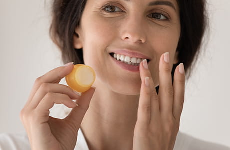A woman applying lip balm.