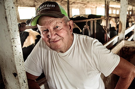 A local dairy farmer takes a moment from his busy day to have a picture taken in the barn.