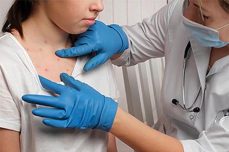 A young female patient is being examined by a provider for measles.